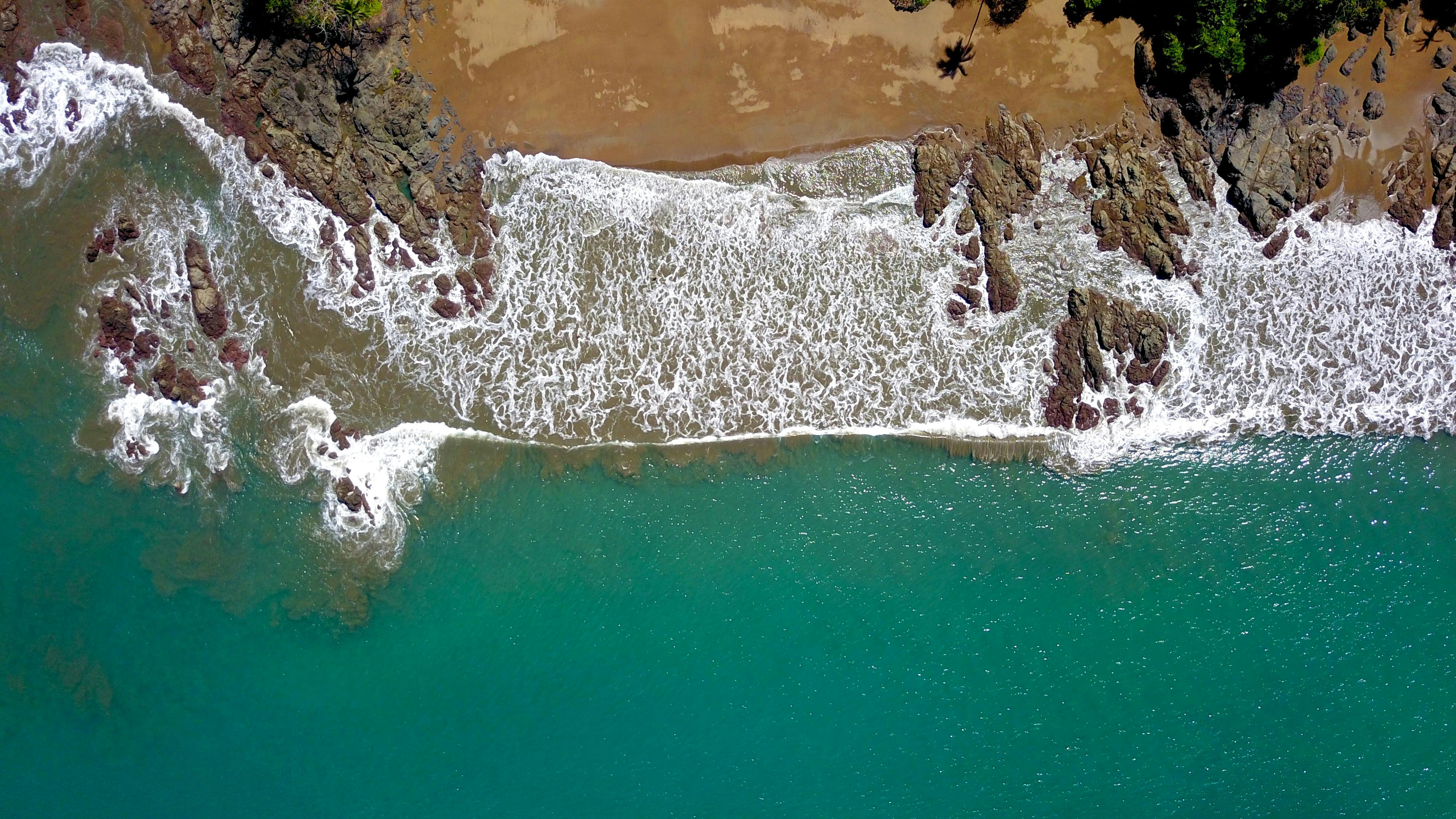 An overhead view of turquoise water meeting a rocky Costa Rica shoreline.