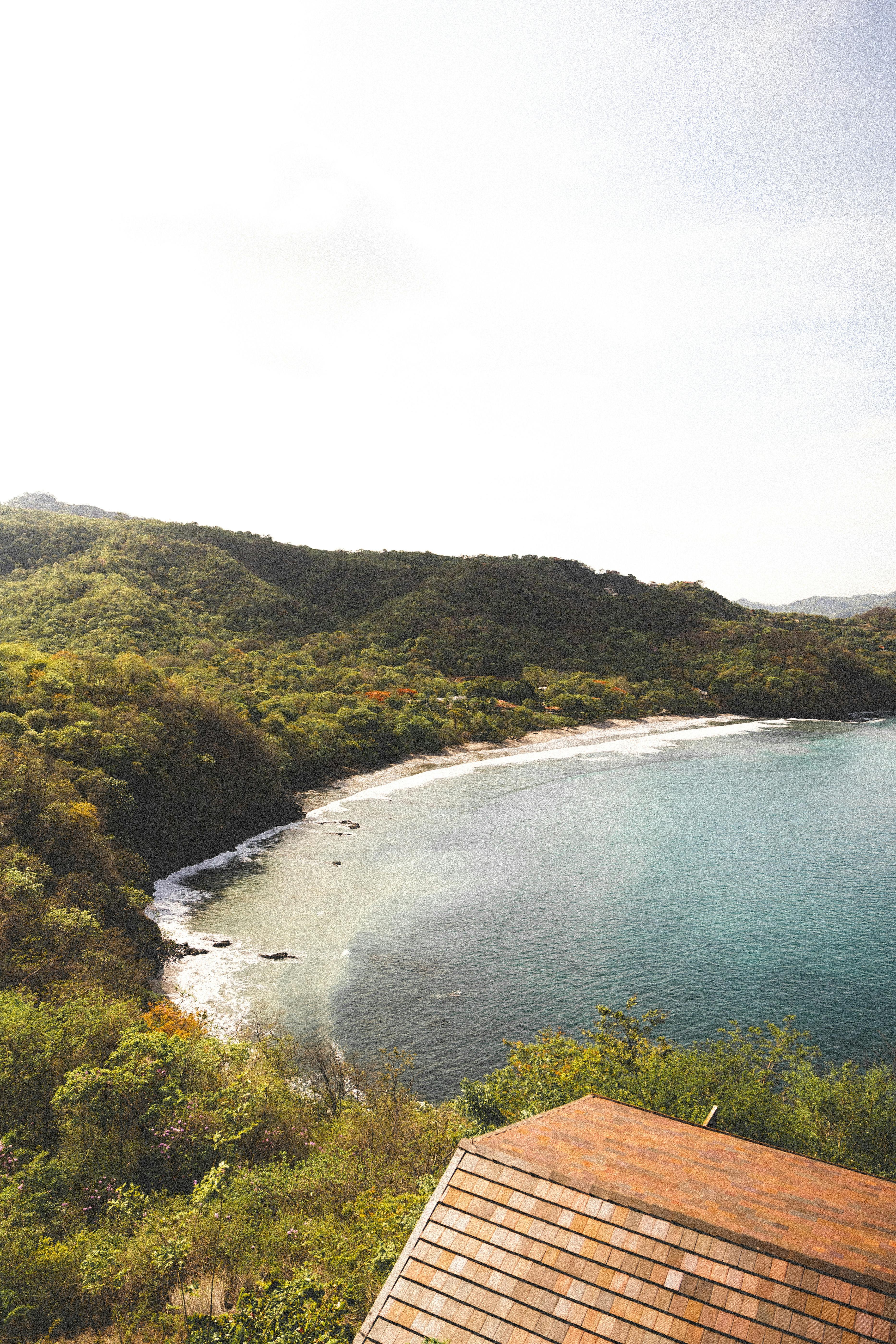 A sheltered Costa Rica cove viewed from above, with green hills and calm water.